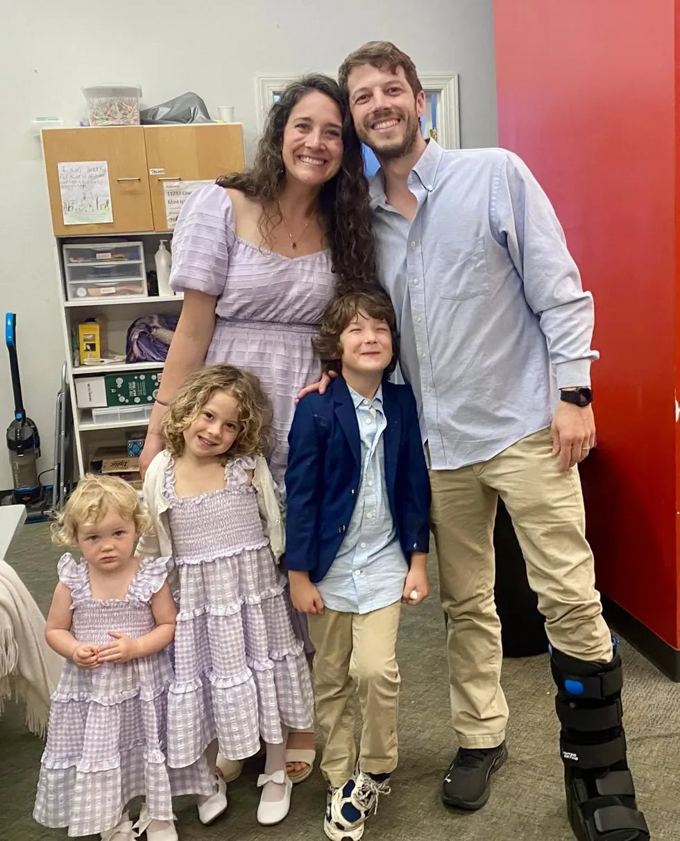 Joshua with his wife and three children, wearing a walking boot, about two months post-op